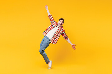 Full body young happy man he wears red checkered shirt casual clothes standing on toes dancing lean...
