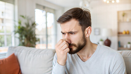 Naklejka premium Man feeling unwell holding hand to his nose experiencing cold symptoms