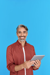 Happy mature man with digital tablet looking at camera standing isolated on blue background. Smiling middle aged professional businessman entrepreneur holding pad advertising online business services.