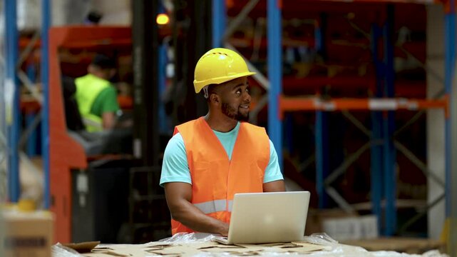 African american male warehouse worker using laptop smiling