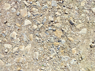 Close-up view of a gravel surface with various stone sizes under bright sunlight in the afternoon