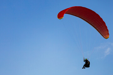 One paraglider is flying in the blue sky against the background of clouds. Paragliding in the sky...