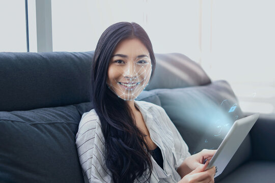 Asian businesswoman usingcomputer tablet scanning  face ID to unlock device security with facial recognition technology for identification, with graphical technology illustration.