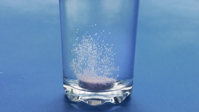 Effervescent tablet dissolving in a glass of water bubbles