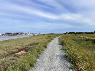 Beautiful landscape of Suffolk coast walk on path near Walberswicj Southwold, no people, with green Summer grass by estuary and ocean with blue skies and light white cloud on holiday in sunshine