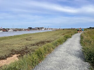 Beautiful landscape of Suffolk coast walk on path near Walberswicj Southwold, no people, with green Summer grass by estuary and ocean with blue skies and light white cloud on holiday in sunshine