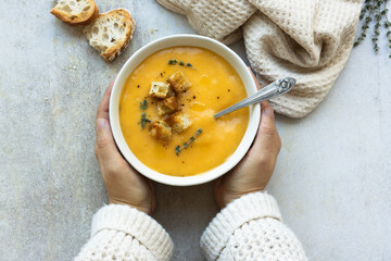 Woman holding a bowl with creamy pumpkin soup. Copy space.