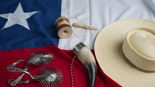 fondo con espuelas, chupalla, cacho emboquillado y emboque sobre la bandera de Chile, concepto celebraci&oacute;n fiestas patrias