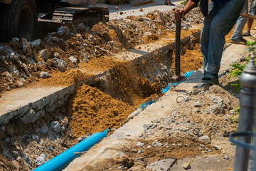 Naklejka premium Construction worker digging trench for pipeline installation in urban area.