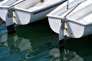 Closeup of two sailboats  with reflection in the calm harbor water.
