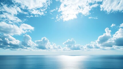 Clear blue sky filled with soft clouds hovering over a vast blue ocean with a peaceful horizon in the distance