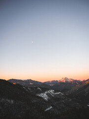 Majestic mountains at twilight, with golden hour light illuminating peaks. Vibrant sunset sky, serene landscape, peaceful atmosphere, remote wilderness, and breathtaking natural beauty.