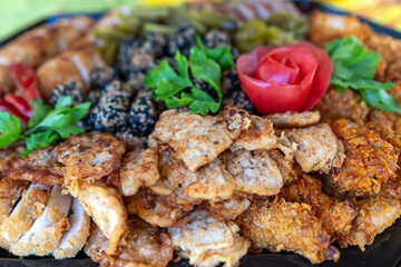 A colorful assortment of grilled and fried meat varieties presented with garnishes and vegetables.