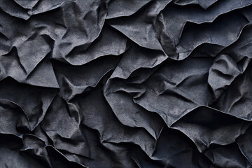 Obraz premium Close-up of dark crumpled fabric with intricate folds and textures, showcasing the depth and complexity of the material's creases and a matte finish.