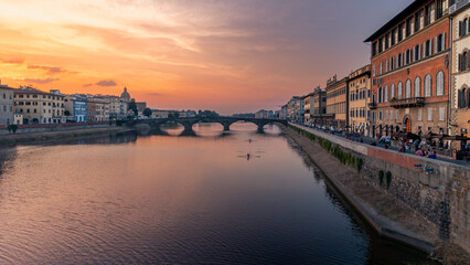Cityscape of Arno river embankment with bridge and buildings of old city at sunset, Florence, Italy