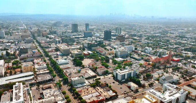 Vast sunny cityscape of Los Angeles, California, the USA. Silhouettes of downtown skyscrapers in the fog at backdrop. Top view.