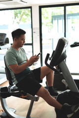 This is a kind of sport injury concept; Asian male athlete sitting on spin bicycle fitness workout...