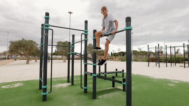 Young athlete is practicing calisthenics in an outdoor gym, showcasing his strength and agility with dynamic routine on parallel bars