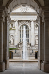 Fototapeta premium A large fountain is in the middle of a large building with a lot of columns. The fountain is surrounded by statues and has a lot of detail
