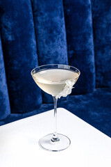 An alcoholic cocktail in a coupe glass garnished with flower petals