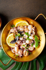 Mini cuttlefish fried with garlic, olive oil and lemon top view vertical photo