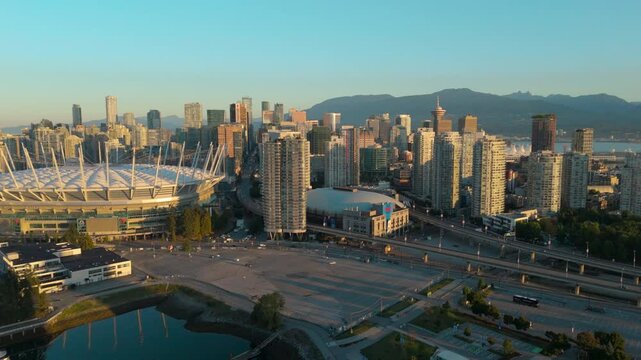 An aerial approach shot of BC Place and downtown Vancouver bathed in morning light