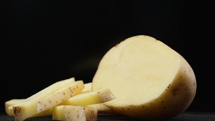 Macrography, the essence of sliced potato against a sleek black background takes center stage. Each...