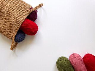 Colorful woolen skeins of yarn for knitting fell out of the handmade basket. Supplies for knitting,...