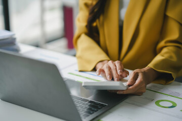 Professional businesswoman analyzing financial data and strategizing investments in her office with tools such as a calculator and charts