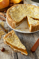 Fall traditional pumpkin pie with cinnamon on a rustic wooden background.