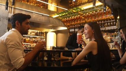 Couple making a toast with cocktail paloma and old fashioned at luxurious bar in lively conversation drinks celebrating a special party at vibrant nightclub while friend drinking Margarita. Vinosity.