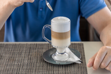 A man is sitting at a table with a cup of coffee in front of him