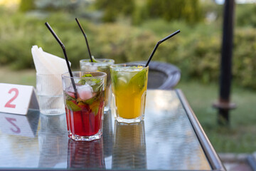 Three drinks with straws in them sit on a table