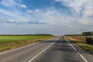 A long, empty road with a few trees in the background