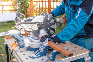 A man is using a power saw to cut a piece of wood