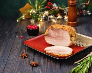 Cold appetizer or hot dish, Christmas pork ham on red square plate on dark wooden background. Holiday dishes.