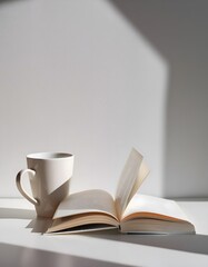 An open book and a coffee or tea cup on a white background, creating a tranquil morning vibe