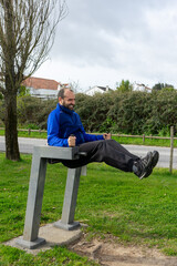 Fototapeta premium Man doing sit-ups on an urban exercise machine in a public park, showcasing fitness and outdoor activity.