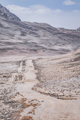 Dusty road of the Pamir Highway winds and twists in the valley of the Tien Shan mountains in Tajikistan in Pamir, landscape in the high desert mountains for background