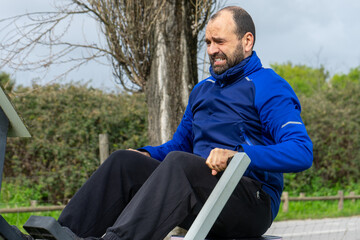 Fototapeta premium Man working out on an urban fitness machine in a public park, focusing on arm and chest exercises, embodying an active and healthy lifestyle.
