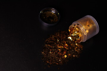 transparent jar with golden shiny shiny glitter on a black background