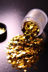 transparent jar with golden shiny shiny glitter on a black background