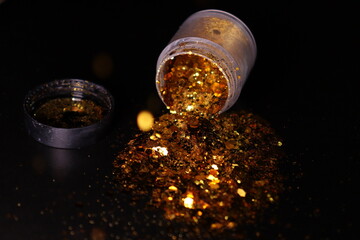 transparent jar with golden shiny shiny glitter on a black background