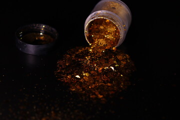 transparent jar with golden shiny shiny glitter on a black background