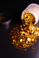 transparent jar with golden shiny shiny glitter on a black background