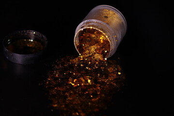 transparent jar with golden shiny shiny glitter on a black background