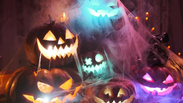 Damn beautiful halloween decorations with lots of carved pumpkins jack o lanterns in cobwebs dry leaves and creepy candles, holiday background.