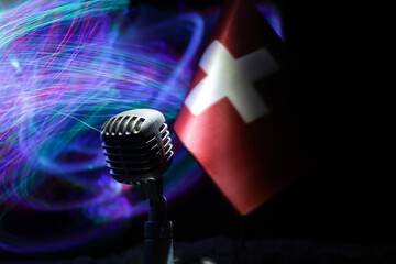 Microphone on a background of a blurry flag of Switzerland close-up. dark table decoration