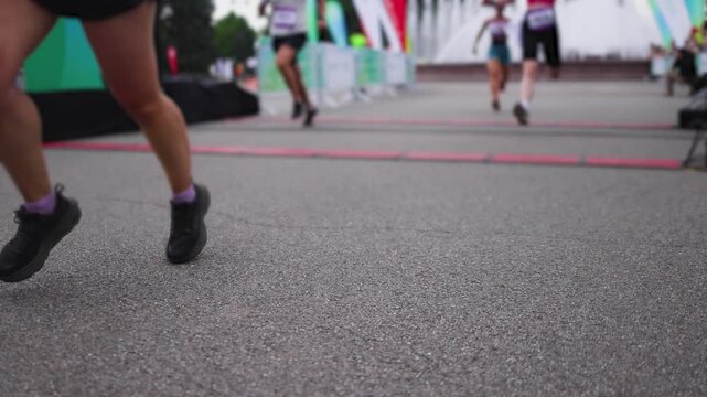 Marathon runners crowd, sportsmen participants start running the half-marathon in the city streets, crowd of sportswomen joggers in motion, group athletes outdoor training competition in a summer day