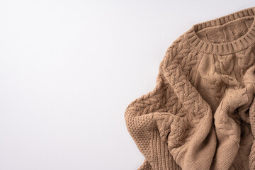 Warm and cozy knitted brown sweater resting on a soft neutral background, perfect for seasonal fashion and comfort